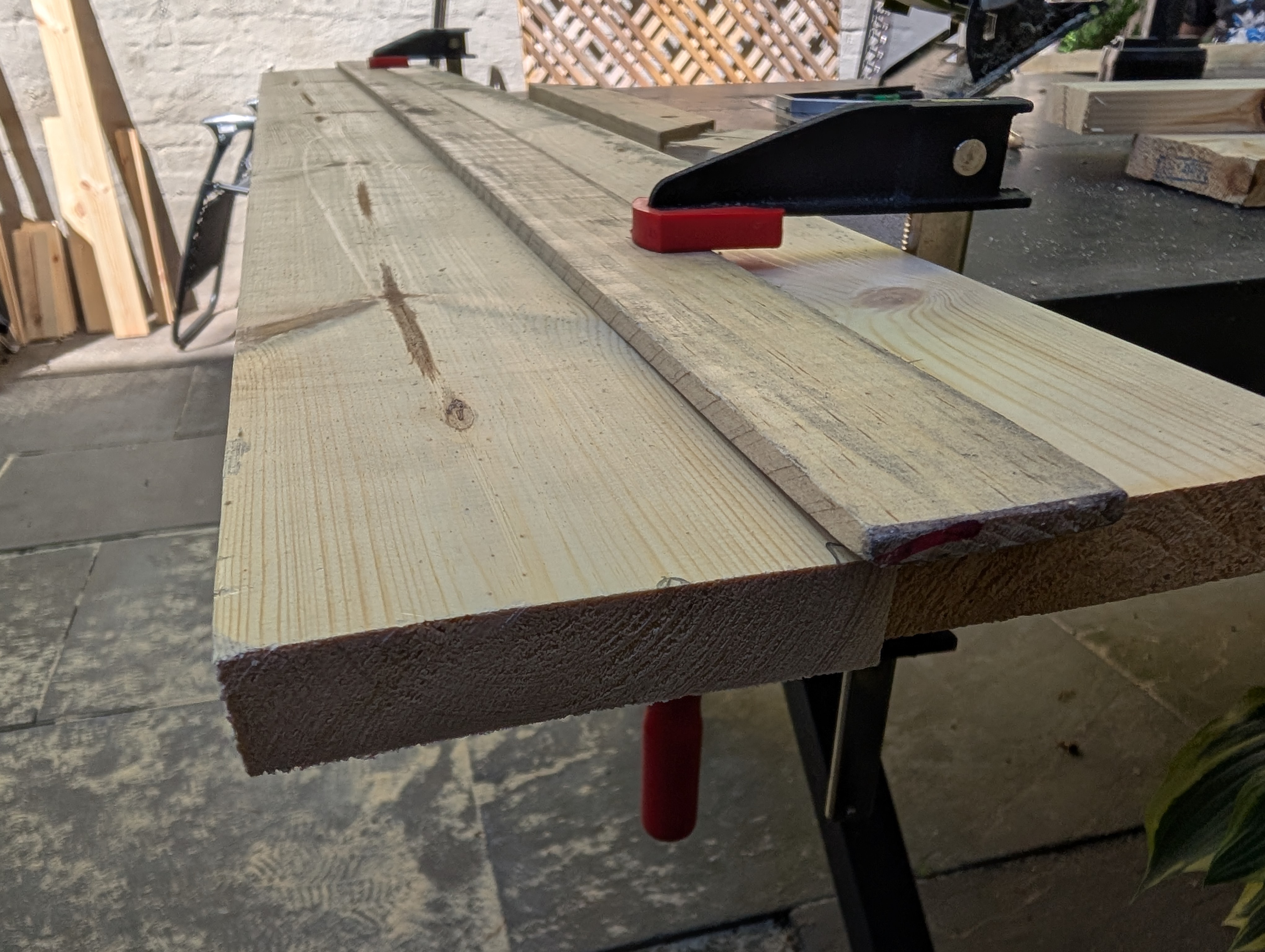 a long straight piece of wood clamped as a guide over a board
